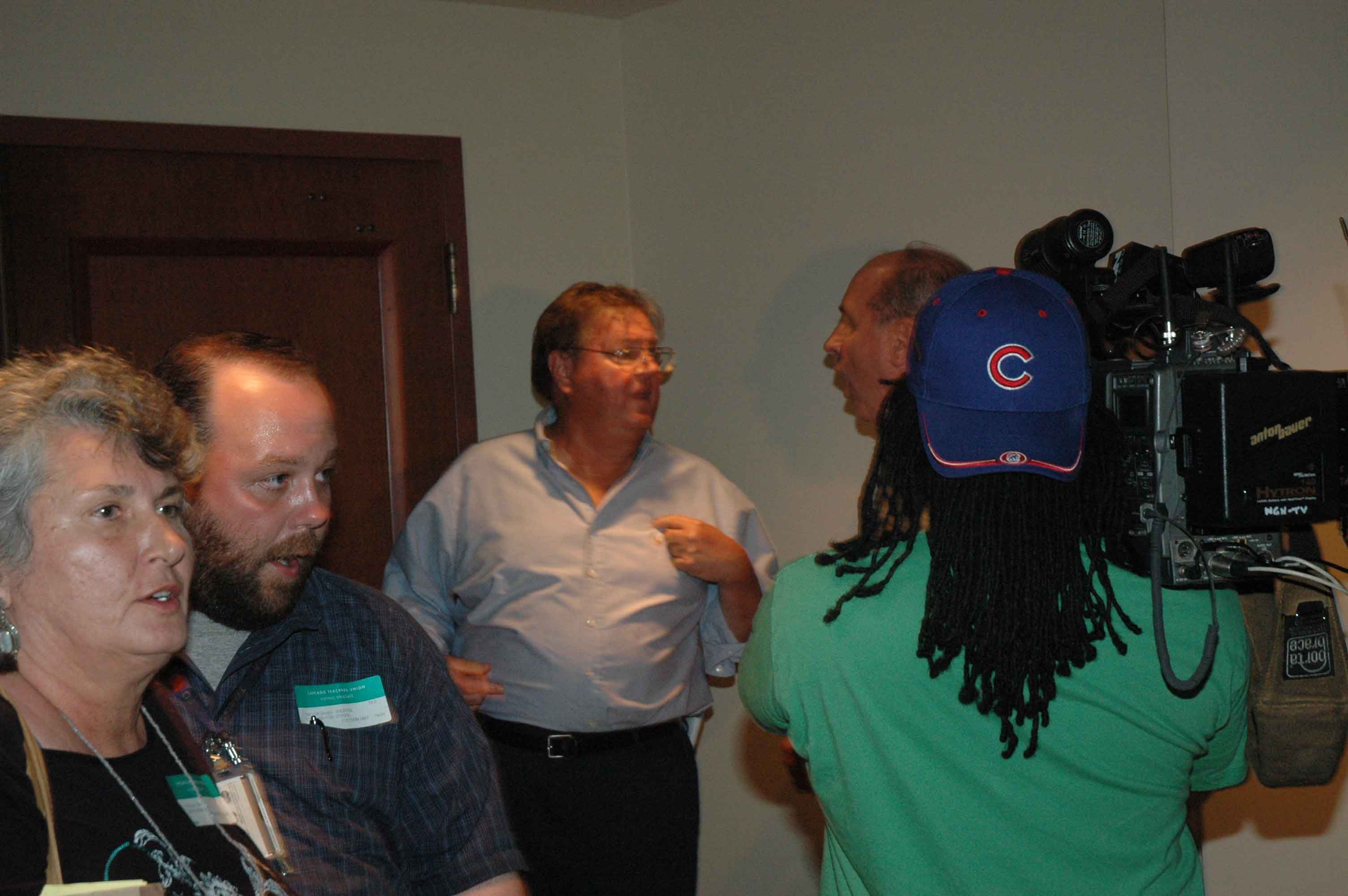 August 31, 2007. While TV cameras rolled, CTU attorney Lawrence Poltrock (center) argued with Roosevelt High School delegate Bill Malugen (partly obscured by camera) during the protests at Plumber’s Hall after the “vote” on the proposed contract brought in by Marilyn Stewart. Some observers at the time thought the two were about to come to blows. Poltrock’s law partner, his daughter Jennifer Poltrock, had served as “parliamentarian” at the raucous union meeting, which was convened on the Friday of Labor Day weekend to review Stewart’s contract proposal, and the big question before the city was whether the teachers were going to go on strike. By halfway through the meeting, the majority of the delegates were either skeptical about the Stewart proposal or opposed to it. Instead of allowing the delegates to ask questions and debate the contract for as long as necessary, Stewart claimed that the meeting had to clear the hall early. When the vote was finally called, Stewart called for the “Yes” votes. Then — despite an outcry from the delegates — she refused to call for the “No” votes and refused to heed calls for a count of the vote. At that point, Stewart simply ruled “The Ayes have it.” It was the first time in history that a vote of the House of Delegates on a CTU contract was not done by counting both the “Yes” and “No” votes. Jennifer Poltrock quickly claimed that Stewart didn’t have to count the “No” votes. Almost as quickly, Stewart disappeared. Stewart and the union officers went downstairs through a back door for a press conference. There, they tried to tell the media that the union delegates supported the contract, when in fact there had been no “No” votes allowed. Most of the delegates believed that had the “No” votes been taken, the contract would have been defeated. Stewart’s press conference was interrupted by chants of “No! No! No!” from hundreds of delegates who refused to leave the building. The delegates assembled outside the door of the press conference (doors behind Poltrock, above). The reporters who had been taking notes on what Marilyn Stewart was saying slowly left the room — despite attempts by CTU security to block the door — and covered the story among the mass of delegates chanting in opposition to the proposed contract. Substance photo by George N. Schmidt