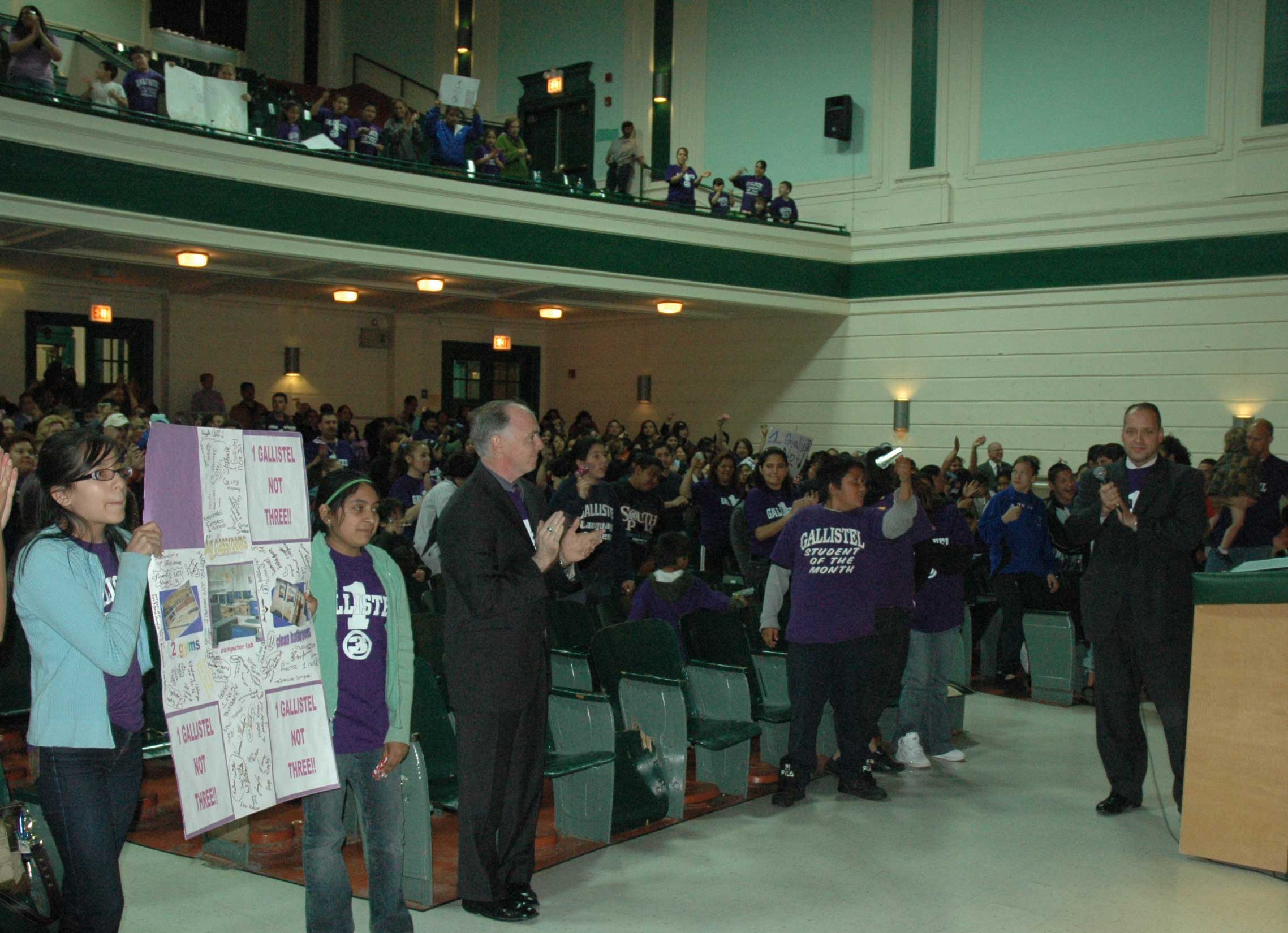 Holding a sign and wearing purple tee shirts that read “One Gallistel, Not Three”, more than 600 students, teachers, parents, and community supporters nearly filled the auditorium at Morgan Park High School on May 22, 2008. The Gallistel Elementary School contingent arrived by car and in 13 buses, making them the largest contingent to testify during the six-day hearings on the Board of Education’s Capital Development program in May. Standing at the podium on the right (above) and wearing his Gallistel tee shirt is Alderman John Pope (10th Ward) who spoke about the need for a new Gallistel school to consolidate the present three-school reality. Gallistel supporters filled most of the main floor of the large auditorium and the front row of the balcony. Whether Gallistel ever gets relief from its problems is another question, one not answered by the officials who hosted the hearings. Since Arne Duncan became CEO of the Chicago Public Schools in July 2001, schools like Gallistel, which proudly proclaim that they are public schools, have been short changed in all capital expenses, while school improvement and construction budgets are manipulated to support privatization schemes and other programs promoted by Chicago Mayor Richard M. Daley. Substance photo by George N, Schmidt.