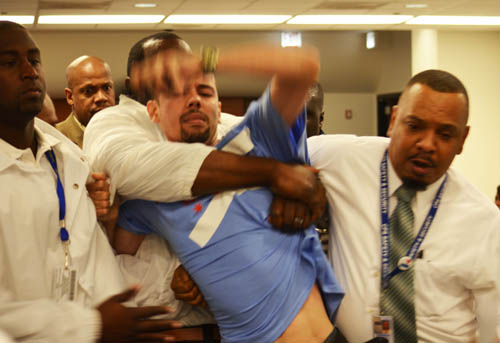 Three Board of Education security staff wrestled Jesus Burgos and dragged him out of the January23, 2014 meeting of the Chicago Board of Education after he told them to stop harassing his wife, Rousemary Vega. The two, along with their children, were at the Board meeting, where Ms. Vega had registered to speak against the priorities of the proposed 2014 - 2015 budget. When Board member Jesse Ruiz, who claimed to represent the north side Latino community, began leaving the Board chambers as criticisms of Board members' hypocrisy grew. Vega said 