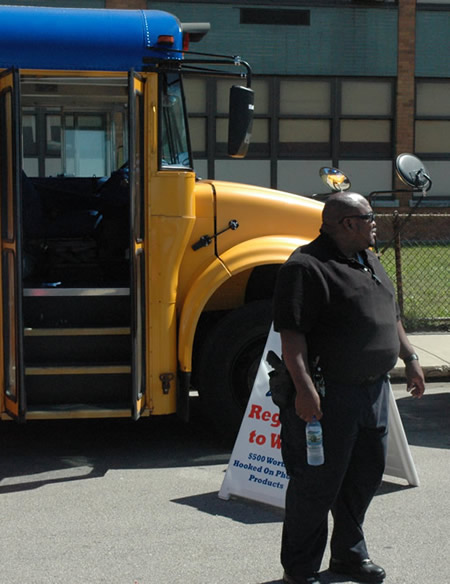 Armed private security guards protect Hooked on Phonics treasures, above: Neither Hooked on Phonics nor Chicago Teachers Union explained when asked why there were three heavily armed private security guards, all wearing bullet proof vests (as above), at the Attucks school Hooked on Phonics event on August 30. The guards confirmed for Substance that they were working for Hooked on Phonics, but refused to identify themselves or explain whom or what they were hired to guard — from whom or what. Substance photo by George N. Schmidt. 